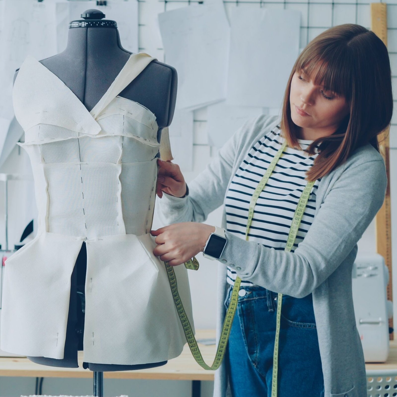 The "Insider Secret" Vibe Female fashion designer measuring a dress form in a creative studio workspace.